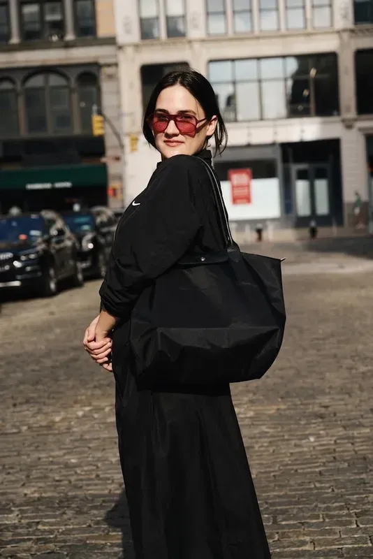 Oversized black nylon tote carried on a cobbled street